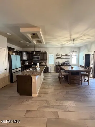 a living room with stainless steel appliances kitchen island granite countertop a stove and a refrigerator