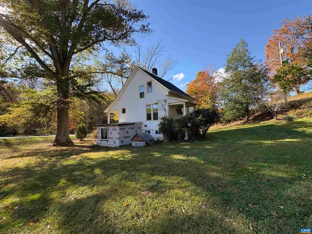 a view of a house with a big yard and large trees