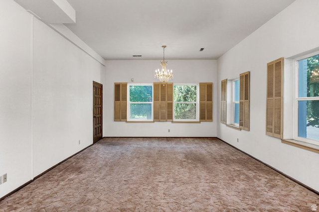 299 West Center Street, Unit 2 Logan, UT 84321 - Photo 7 of 46 Spacious interior room featuring multiple windows with louvered shutters, a paneled door, and a chandelier
