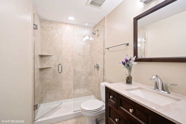 a bathroom with a granite countertop sink a toilet and shower