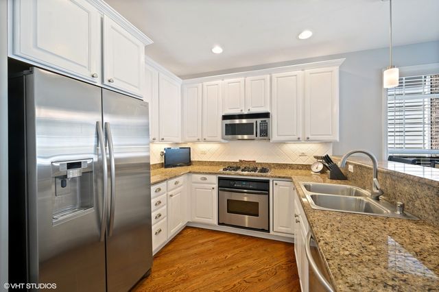 a kitchen with stainless steel appliances granite countertop a refrigerator a sink a stove with cabinets