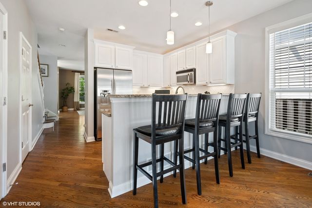 a kitchen with stainless steel appliances granite countertop a dining table chairs refrigerator sink and cabinets