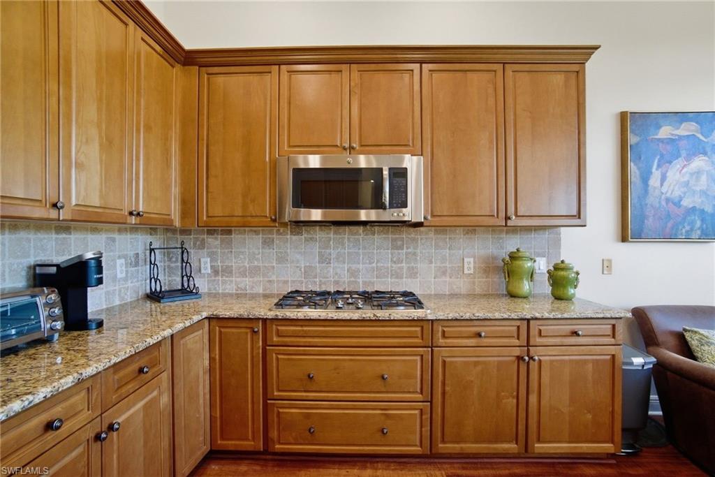 17015 Porta Vecchio Way, Unit 101 Naples, FL 34110 - Photo 8 of 39 a kitchen with stainless steel appliances wooden cabinets and a stove top oven