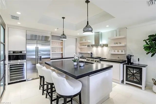 a kitchen with stainless steel appliances granite countertop a sink a stove a refrigerator and island