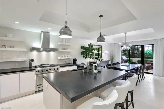 a kitchen with stainless steel appliances granite countertop a stove a sink a dining table and chairs with wooden floor