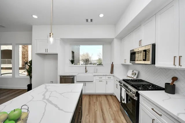 a kitchen with stainless steel appliances a stove a sink cabinets and a wooden floor