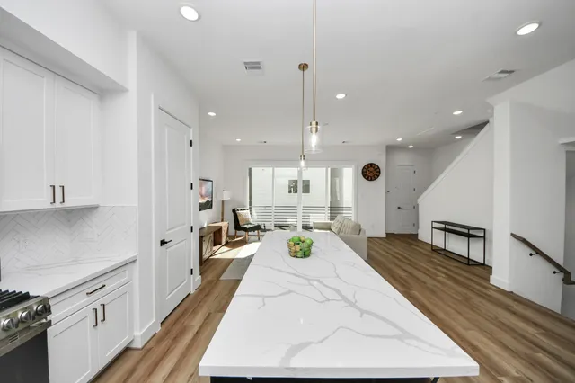 a large white kitchen with wooden floor and stainless steel appliances