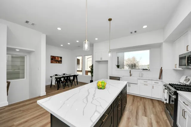 a large kitchen with kitchen island a stove a sink a dining table and chairs