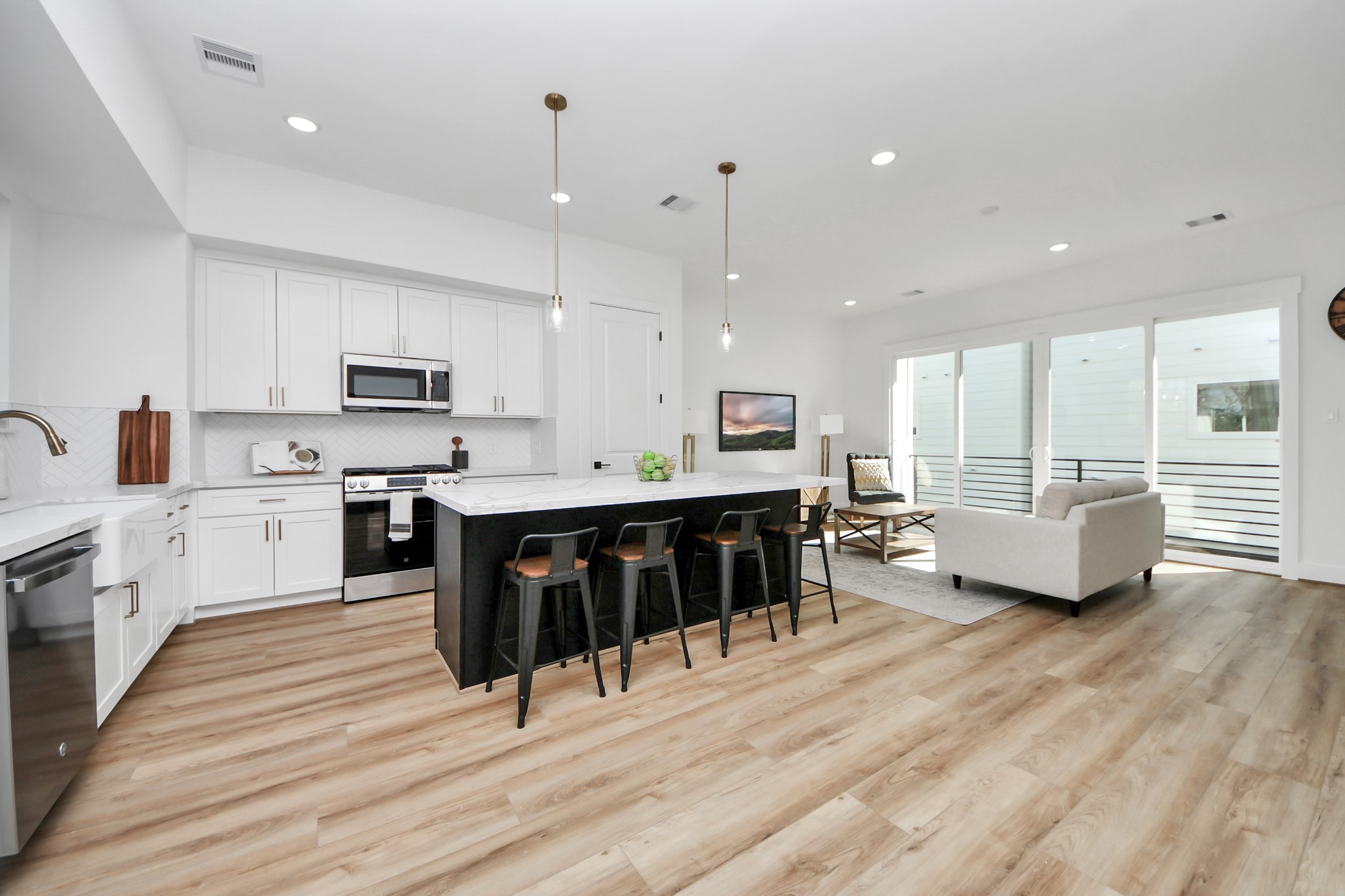 4804 Elysian Street, Unit B Houston, TX 77009 - Photo 21 of 49 a large white kitchen with kitchen island granite countertop a stove top oven a sink a dining table and chairs with wooden floor