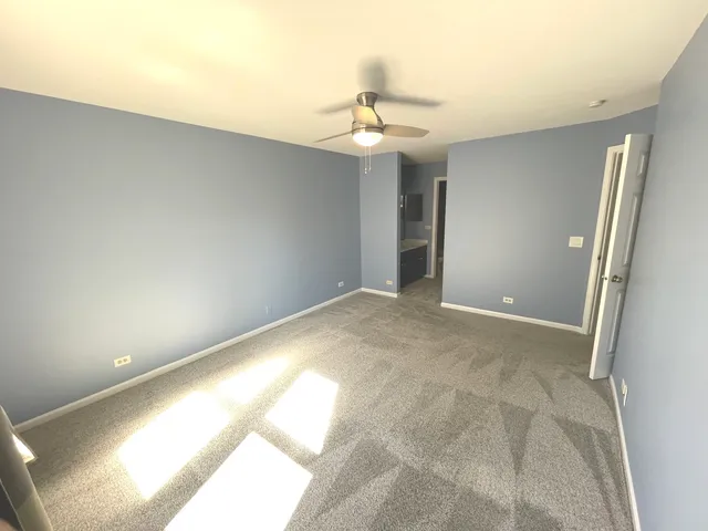 a view of an empty room and chandelier fan