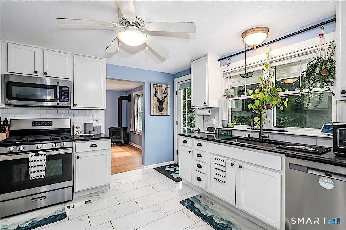 313 Torrington Road Litchfield, CT 06759 - Photo 7 of 26 Bright, Inviting Kitchen Featuring Crisp White Cabinetry, Granite Countertops, Tiled Flooring and Stainless-Steel Appliances