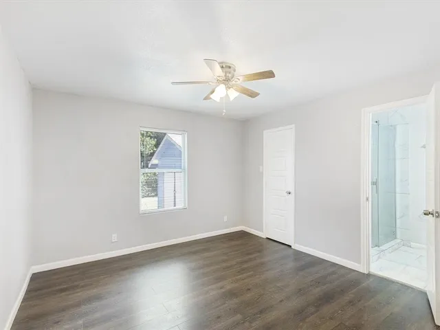 an empty room with wooden floor ceiling fan and windows