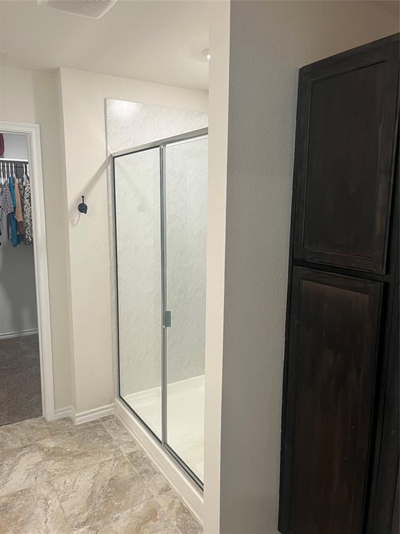 723 Primrose Lane Pilot Point, TX 76258 - Photo 15 of 37 Bathroom with a shower stall and a spacious walk-in closet and built-in linen and storage cabinet