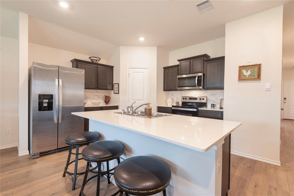 723 Primrose Lane Pilot Point, TX 76258 - Photo 23 of 37 Kitchen with appliances with stainless steel finishes, decorative backsplash, light wood-style flooring, a breakfast bar area, walk-in pantry and recessed lighting