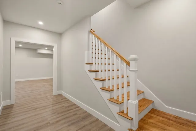 a view of staircase with wooden floor and white walls
