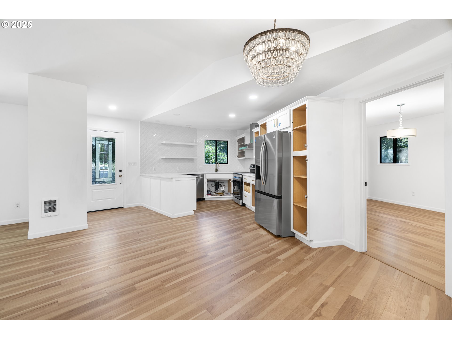 95708 Horton Lane Brookings, OR 97415 - Photo 11 of 46 a view of a kitchen with a refrigerator a kitchen island wooden floor and a living room view