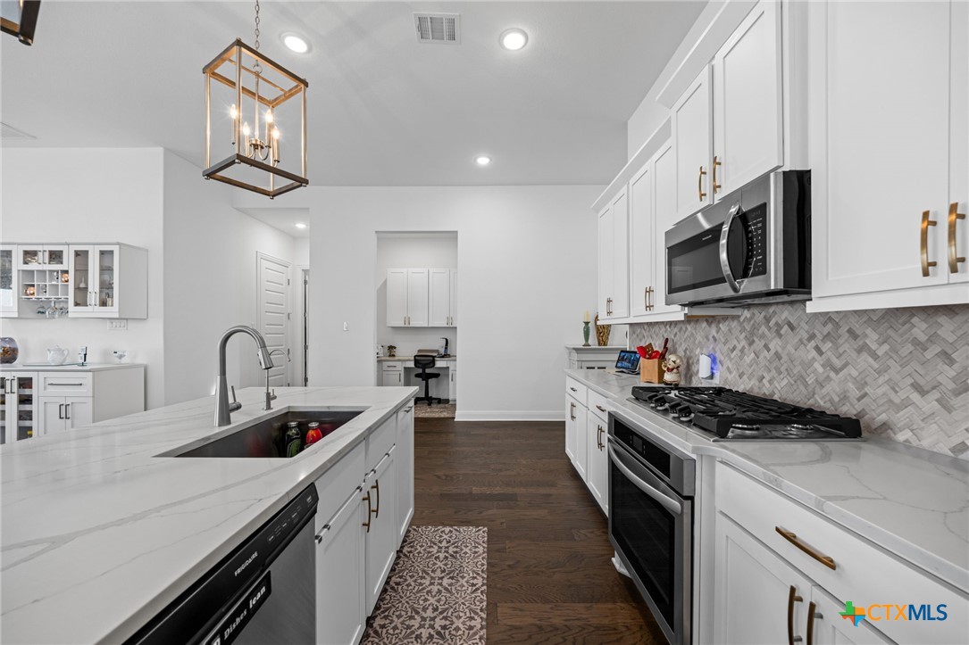 3009 Sage Ranch Drive Leander, TX 78641 - Photo 4 of 43 a kitchen with stainless steel appliances a sink a stove oven a counter top space and cabinets