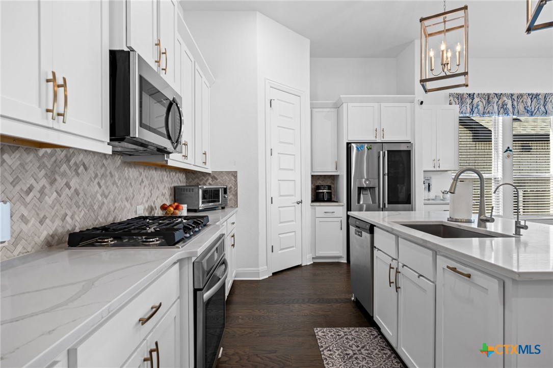 3009 Sage Ranch Drive Leander, TX 78641 - Photo 5 of 43 a kitchen with stainless steel appliances granite countertop a sink stove and refrigerator