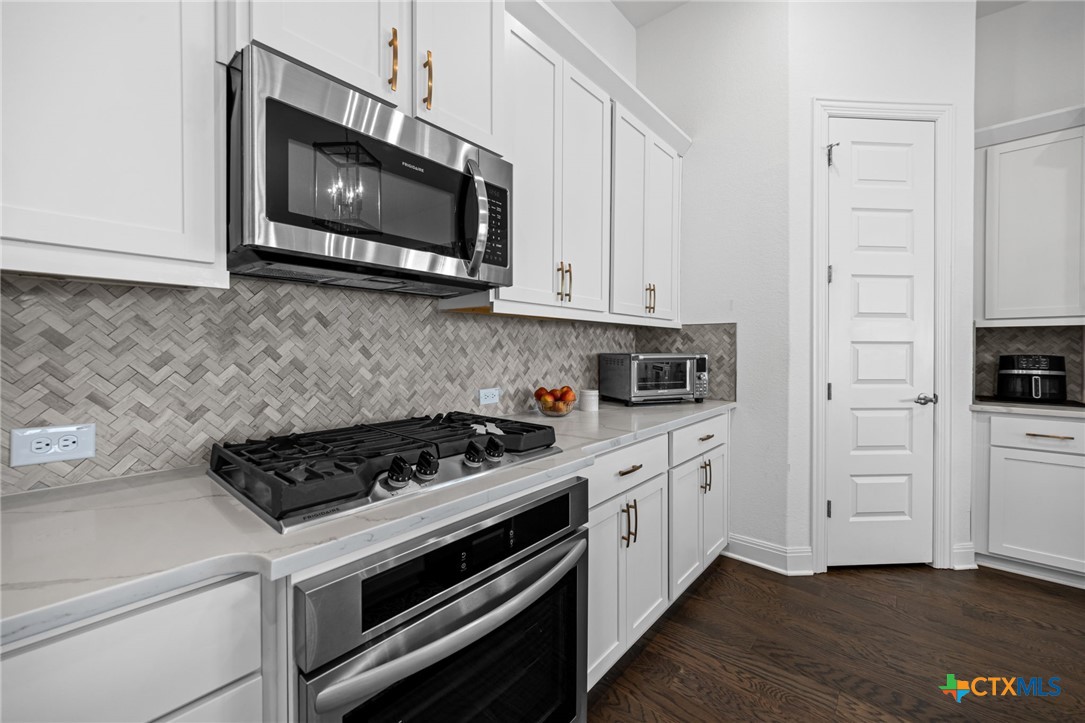 3009 Sage Ranch Drive Leander, TX 78641 - Photo 6 of 43 a kitchen with stainless steel appliances granite countertop a stove a microwave and cabinets