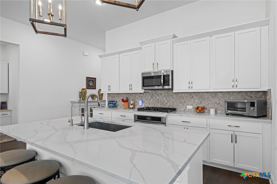 3009 Sage Ranch Drive Leander, TX 78641 - Photo 8 of 43 a kitchen with stainless steel appliances a white cabinets and a stove top oven