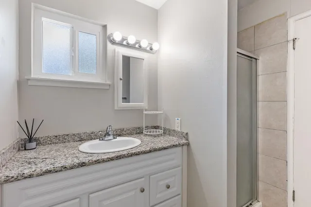 a bathroom with a granite countertop sink and a mirror