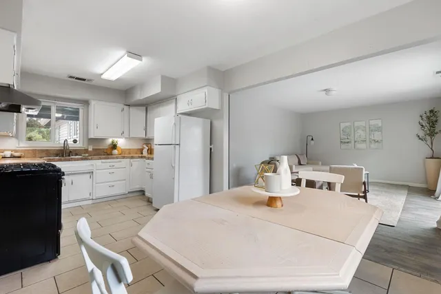 a kitchen with a refrigerator a stove top oven a sink a dining table and chairs