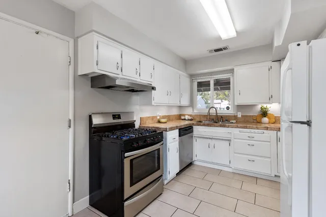 a kitchen with granite countertop white cabinets and stainless steel appliances