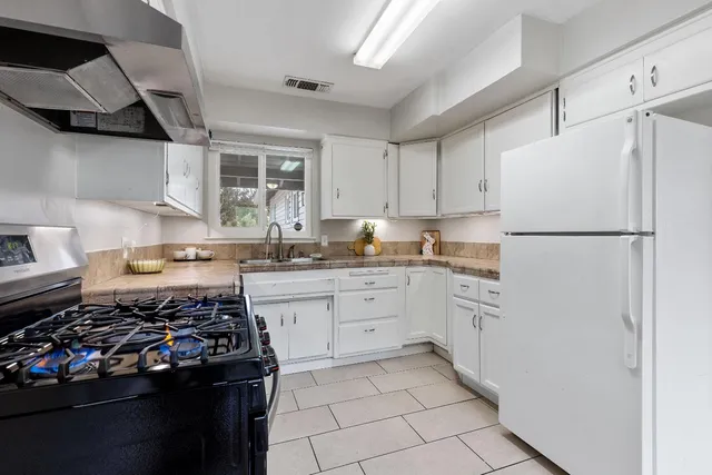 a kitchen with a stove a refrigerator and white cabinets
