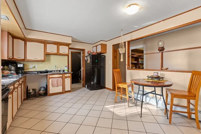 a kitchen with stainless steel appliances kitchen island granite countertop a table chairs and a refrigerator