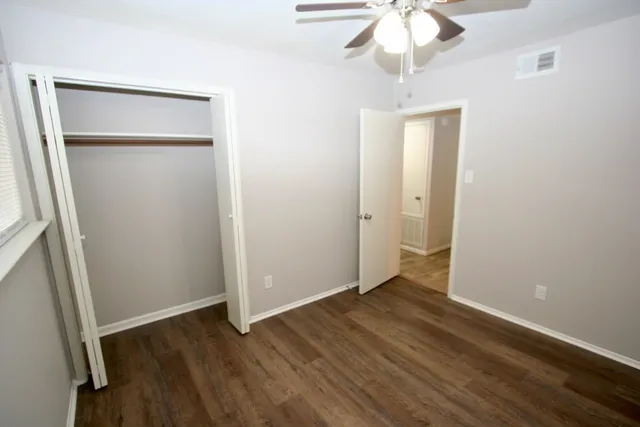 an empty room with wooden floor and fan