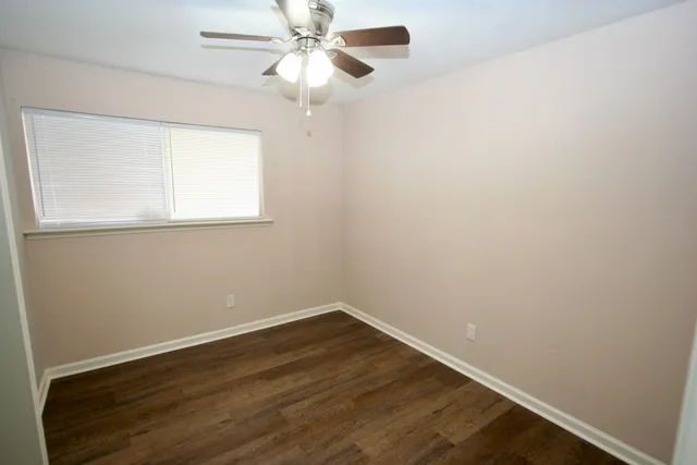 an empty room with a window and wooden floor