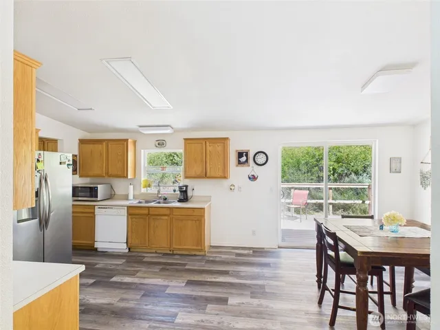 a kitchen with stainless steel appliances granite countertop a stove a refrigerator a kitchen island a table and chairs in it