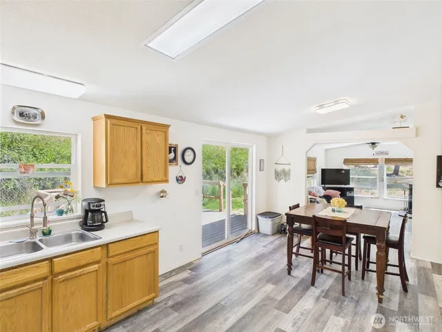 a kitchen with kitchen island granite countertop a dining table chairs and a wooden floor