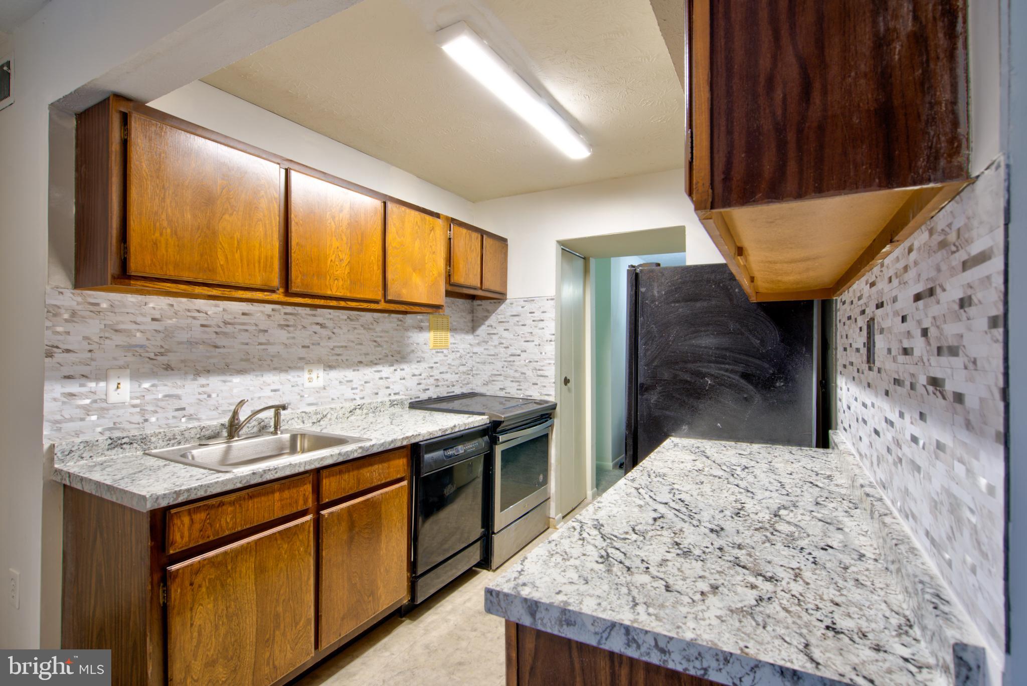 8011 Mandan Road, Unit 201 Greenbelt, MD 20770 - Photo 13 of 28 a kitchen with stainless steel appliances kitchen island granite countertop a sink stove and cabinets