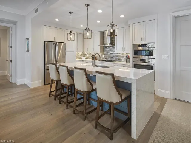 a kitchen with kitchen island granite countertop a sink and a refrigerator