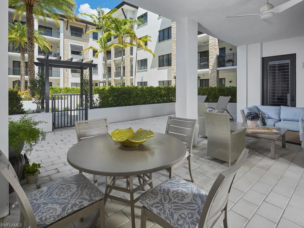 1135 3rd Avenue South Naples, FL 34102 - Photo 20 of 35 a view of a patio with table and chairs potted plants with wooden floor and fence