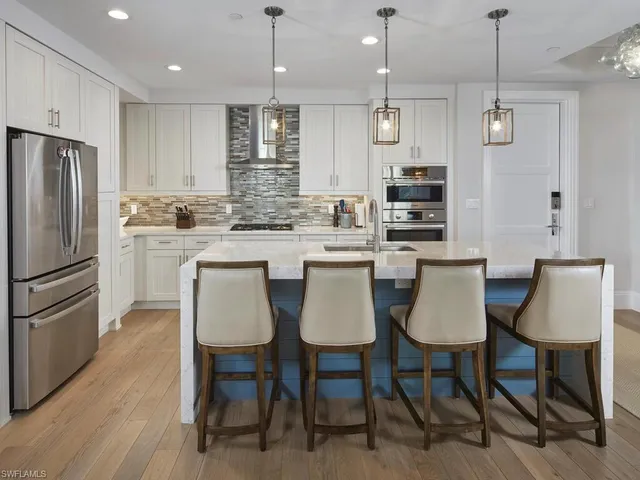 a kitchen with kitchen island granite countertop a dining table chairs cabinets and stainless steel appliances