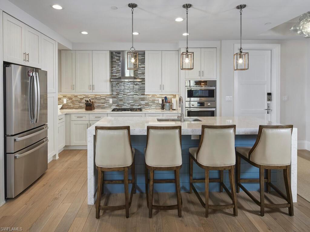 1135 3rd Avenue South Naples, FL 34102 - Photo 9 of 35 a kitchen with kitchen island granite countertop a dining table chairs cabinets and stainless steel appliances