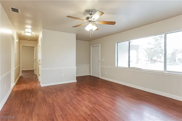 a view of an empty room with wooden floor and a window