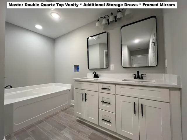 a bathroom with a double vanity sink mirror and bathtub