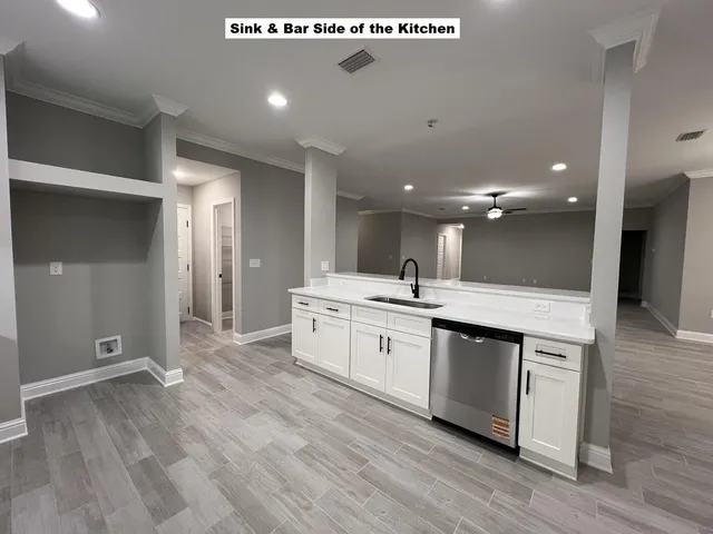 a large kitchen with a large counter top a sink stainless steel appliances and cabinets