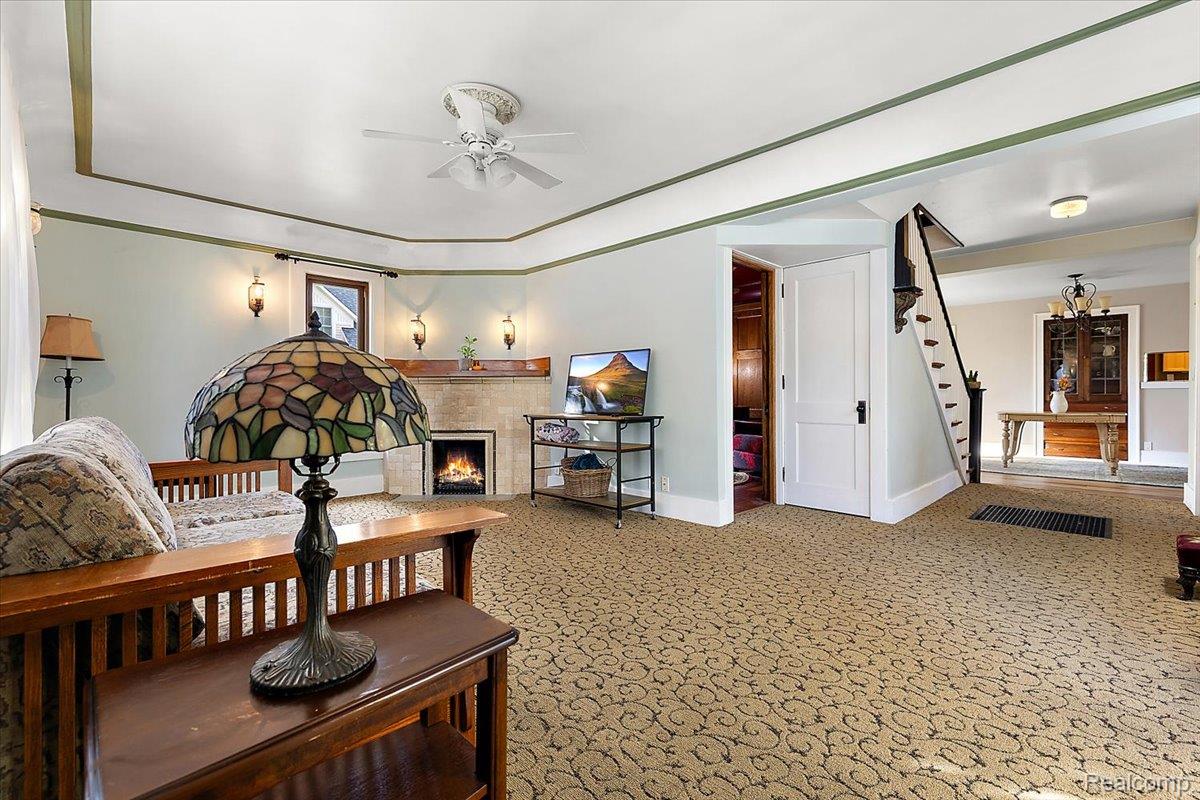 5815 Chicago Road Warren, MI 48092 - Photo 18 of 47 Living area featuring stairway, a warm lit fireplace, carpet, and a ceiling fan