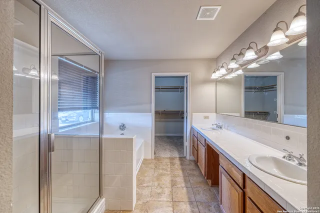 a bathroom with a double vanity sink a large mirror and a shower