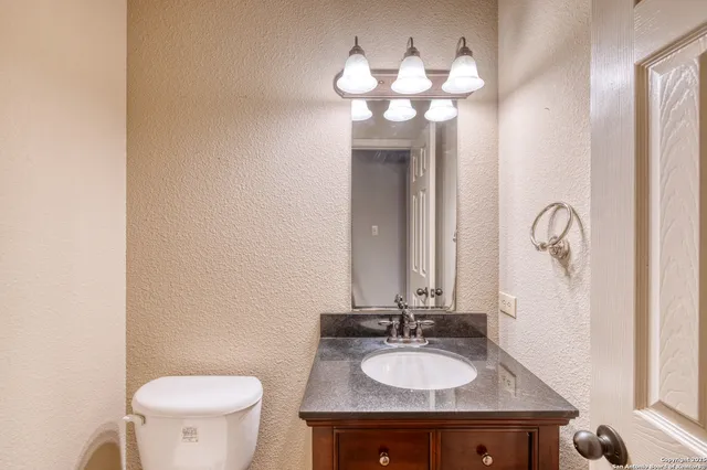a bathroom with a granite countertop sink and a mirror with toilet
