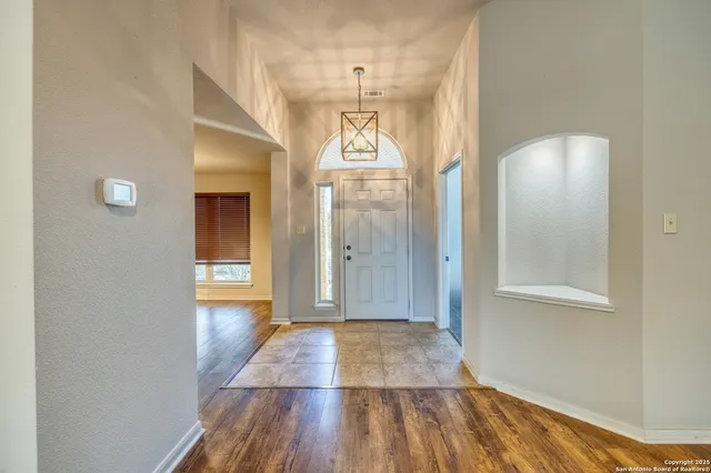 a view of a hallway with wooden floor and a chandelier