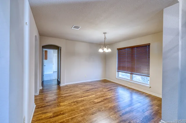 an empty room with wooden floor mirror and windows