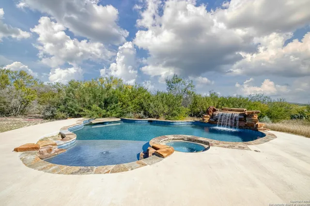 a view of pool with lawn chairs and iron fence