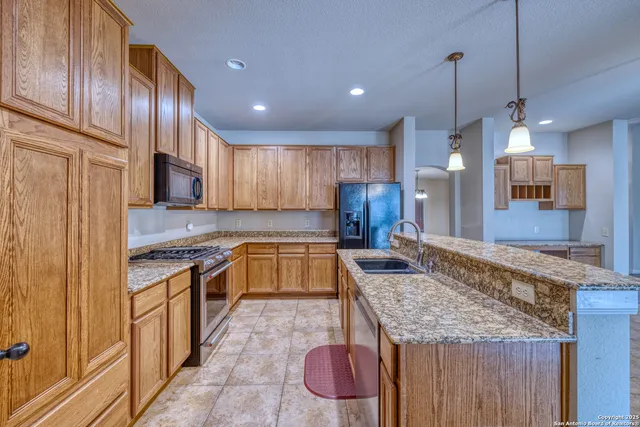 a kitchen with granite countertop kitchen island stainless steel appliances a stove sink and refrigerator