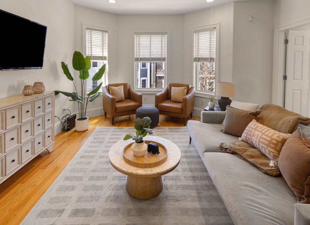a living room with furniture a flat screen tv and a floor to ceiling window