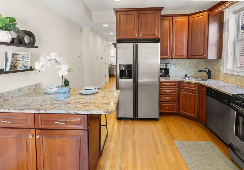 12 I Street, Unit 3 Boston, MA 02127 - Photo 5 of 19 a kitchen with stainless steel appliances granite countertop a refrigerator a sink dishwasher and wooden cabinets with wooden floor